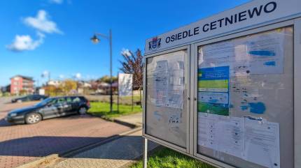 Tablica ogłoszeniowa - Osiedle Cetniewo, w tle miejsca parkingowe dla samochodów przylegające do skweru rekreacyjno-wypoczynkowego Władysławowo - Cetniewo, ul. Jachtowa. fot. Łukasz Grzejszczak Mojeurlopy.pl