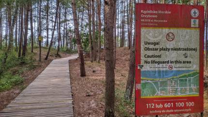 Tablica 'Kąpielisko Morskie Grzybowo, wejście ul. Marynarska'. Drewniany podest do wejścia na plażę. Fot. Łukasz Grzejszczak Mojeurlopy.pl