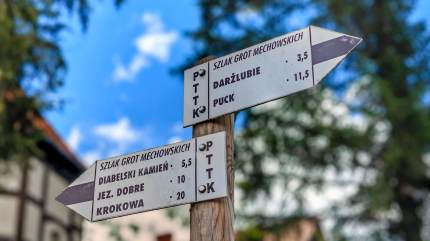 Szklaki turystyczne i rowerowe biegnące przez Mechowo. Tabliczki ze znakami 'Szlaku Grot Mechowskich' wskazujące 'Diabelski kamień', Jezioro Dobre, Krokową, Darżlubie i Puck. Fot. Łukasz Grzejszczak Mojeurlopy.pl